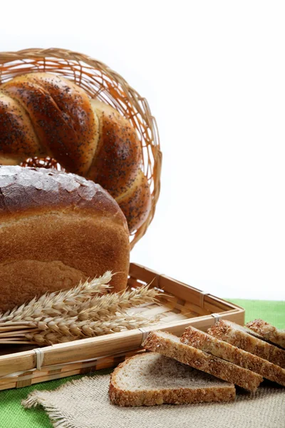 Fresh bread with ears of wheat on a green canvas. — Stock Photo, Image
