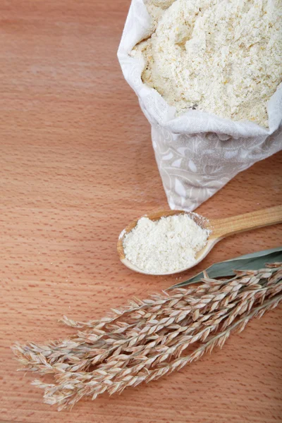 Corn flour in a bag with wooden spoon and ear on wooden table. — Stock Photo, Image