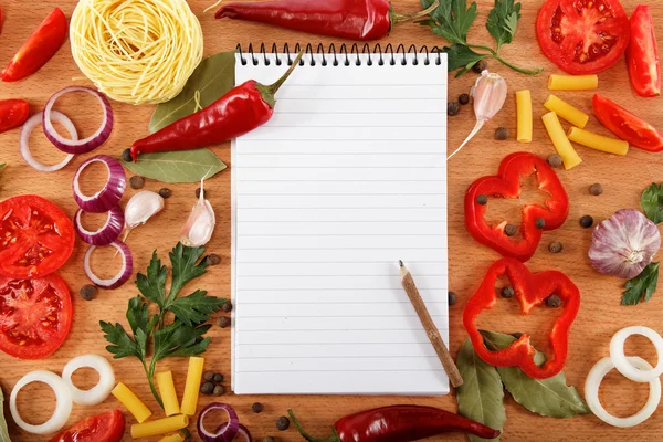 Cuaderno para recetas, verduras y especias en mesa de madera . — Foto de Stock