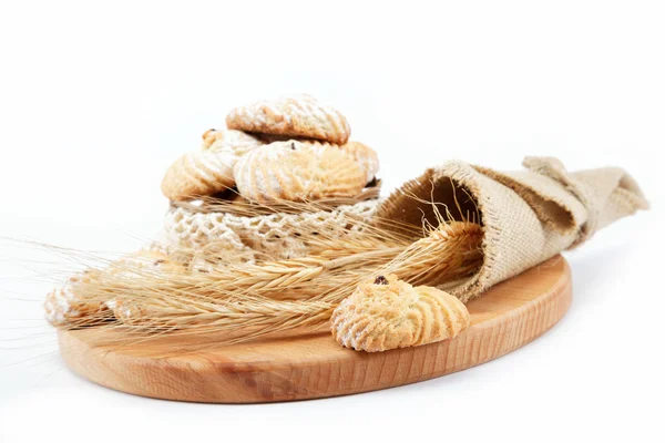 Biscuits avec sucre en poudre dans un paquet de lin et oreilles sur blanc — Photo