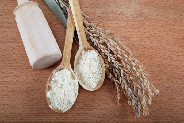 Mąki kukurydzianej w drewnianą łyżką i ucha na drewnianym stole. — Zdjęcie stockowe