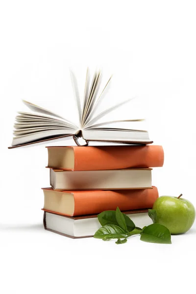 Uma pilha de livros e maçã verde em um fundo branco . — Fotografia de Stock