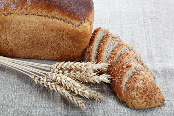 Свежий хлеб с колосьями пшеницы на холсте . — стоковое фото