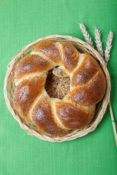 A fresh loaf of bread sprinkle with poppy seeds on a green canva — Stock Photo, Image