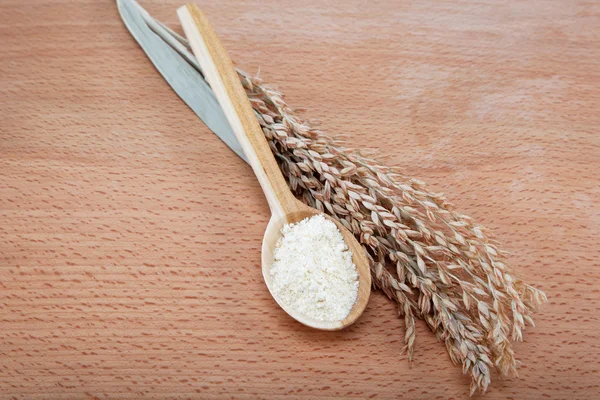 Mąki kukurydzianej w drewnianą łyżką i ucha na drewnianym stole. — Zdjęcie stockowe