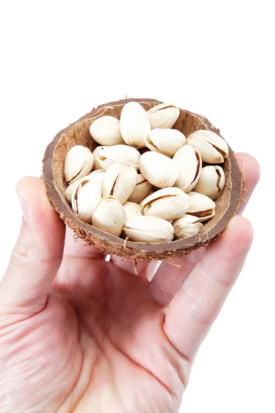 Hand med pistagenötter i en kokosnöt skal, isolerad på vita backg — Stockfoto