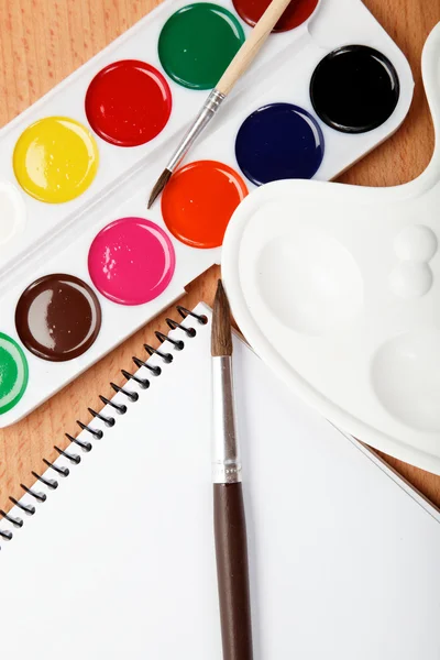 Barva, paleta, Poznámkový blok a brushe na dřevěný stůl. — Stock fotografie