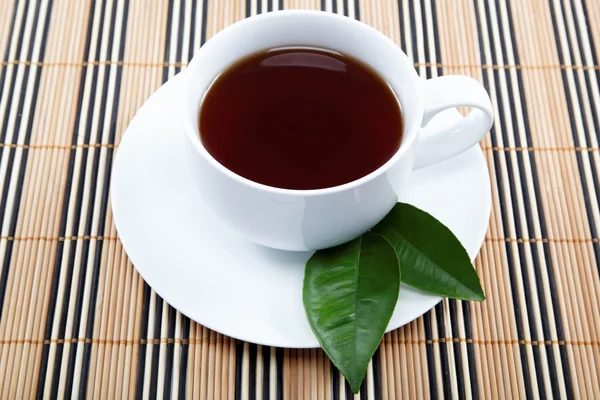 Een kopje van zwarte thee met een schotel op een houten tafel. — Stockfoto