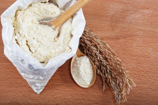 Farina di mais in un sacchetto con cucchiaio di legno e spiga sul tavolo di legno . — Foto Stock