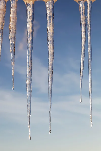 Icicles in the sunny day against a blue sky with white clouds. — Stock Photo, Image