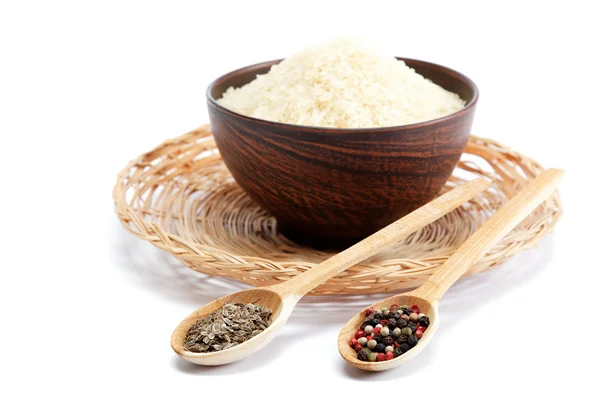 Granos de arroz en un tazón y dos cucharas de madera con isola de especias —  Fotos de Stock