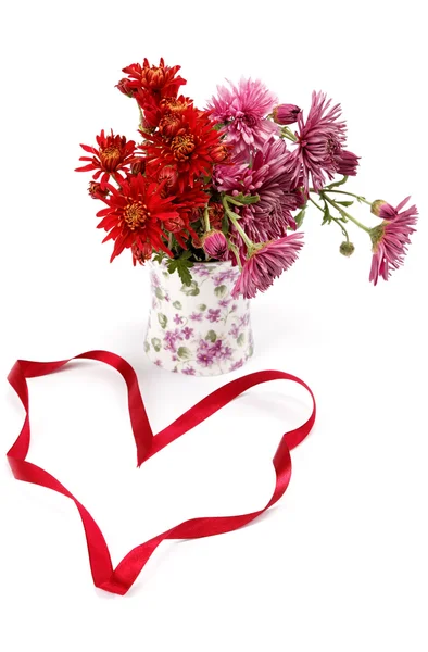 Fiori di crisantemo in un vaso di vetro e un nastro rosso festivo o — Foto Stock