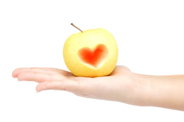 Woman's hand holding an apple with a carved image of the heart o — Stock Photo, Image