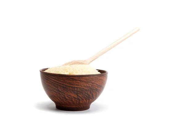 Grains de riz dans un bol et cuillère en bois isolé sur le dos blanc — Photo