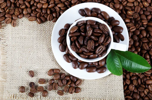 Cup with coffee beans on sackcloth. — Stock Photo, Image