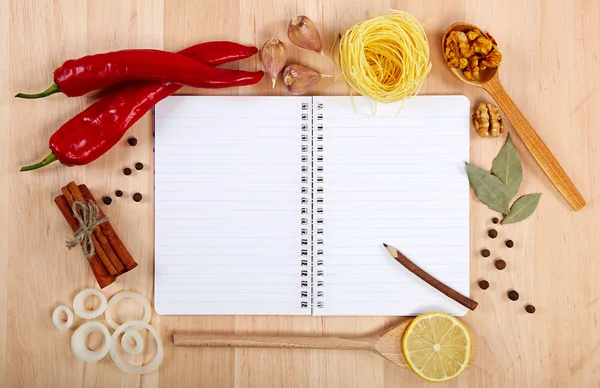 Notebook pro recepty, zeleniny a koření na dřevěný stůl. — Stock fotografie