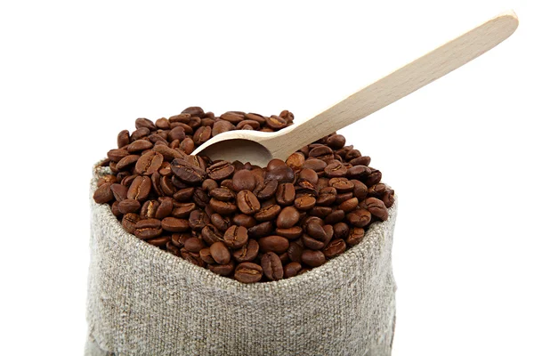 Kaffebönor i en väska och en träslev på en vit backg — Stockfoto