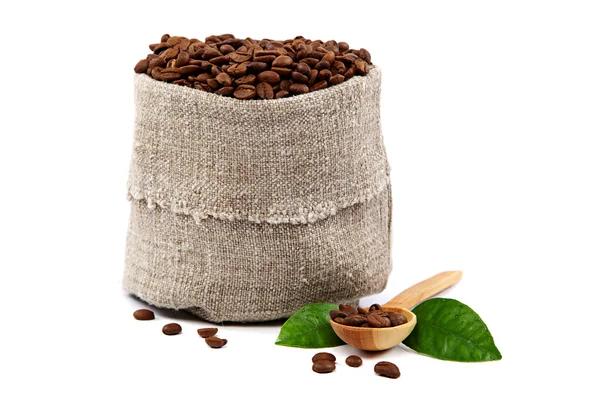 Coffee beans in a canvas bag, wooden spoon and green leaves. — Stock Photo, Image