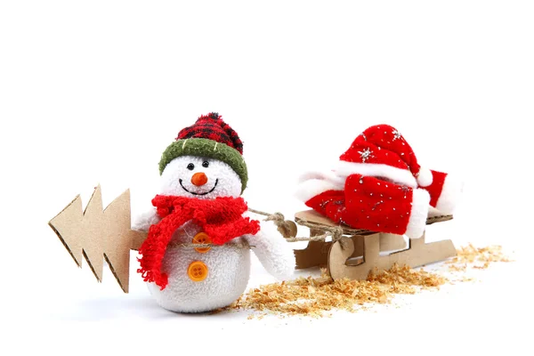 Snowman with sledge, Christmas tree and Santa Claus clothes. — Stock Photo, Image