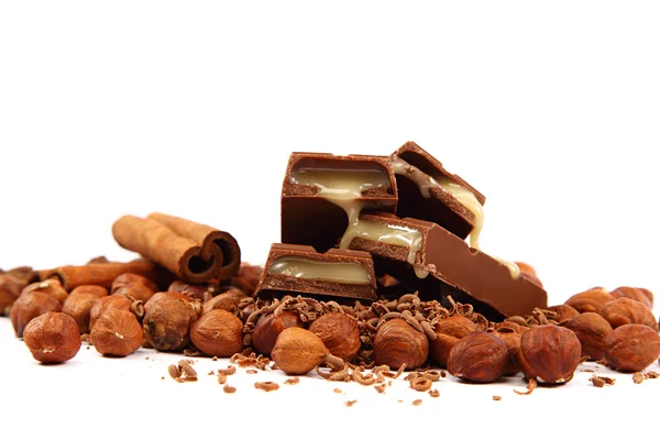 Stack of chocolate tiles with hazelnuts and cinnamon sticks. — Stock Photo, Image