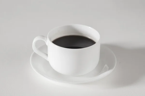 Caffè nero in tazza su tavolo bianco — Foto Stock