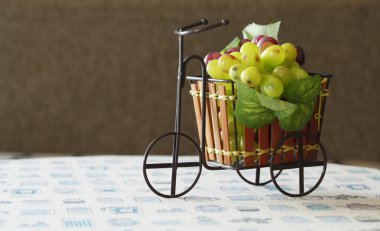 βιολετί και πράσινα σταφύλια στο χαριτωμένο μικρό ποδήλατο