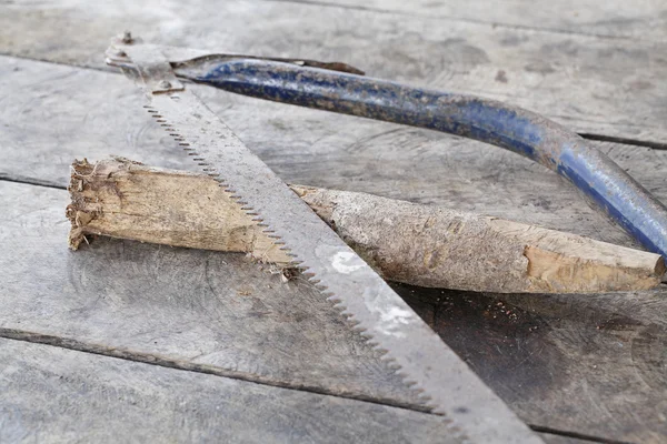 Oude zag met hout op houten tafel — Stockfoto