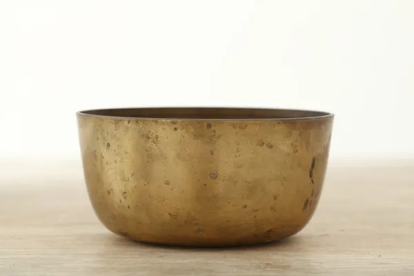 Old brass bowl on wooden table — Stock Photo, Image