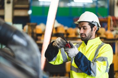Güvenlik kasketli profesyonel teknisyen. Endüstriyel fabrikada inşaat malzemelerinin bakımında çalışıyor. Teftiş görevlisi üretim teknolojisi işiyle uğraşıyor.