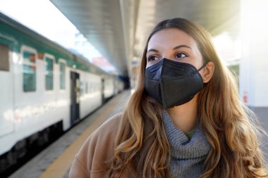 Tren istasyonunda siyah koruyucu maske takan genç bir kadının portresi KN95 FFP2
