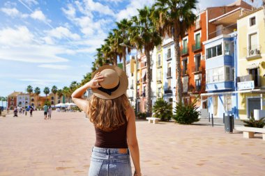 Avrupa 'da turizm. Palmiye ağaçları ve plajlarla dolu renkli İspanyol köyünü ziyaret eden mutlu gezgin kız Villajoyosa, Alicante, İspanya.