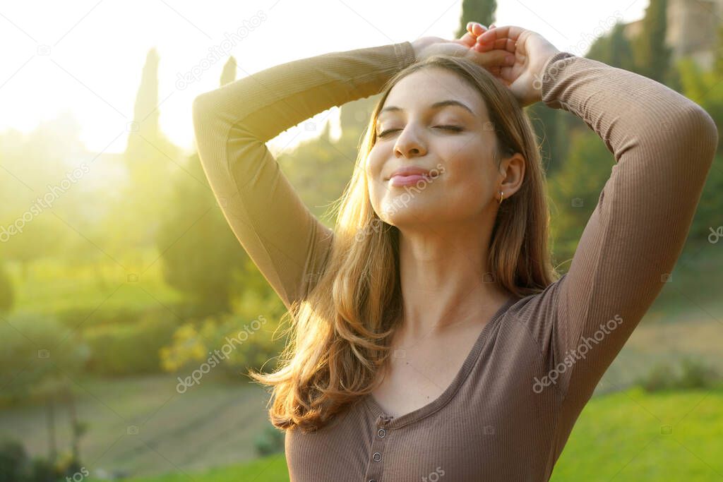 Portrait of free woman breathing clean air in nature. Happy girl with raised arms in bliss. Relaxing, quietness outdoor, wellness healthy lifestyle concept.