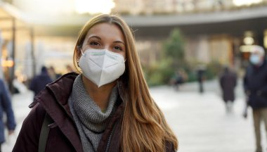 Virüse karşı korunmak için şehir caddesinde tıbbi maske takan kendine güvenen kadınlara yakın durun.