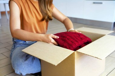 İkinci el kıyafetler. Güzel genç bayan bağış kutusunu giysiyle hazırlıyor..