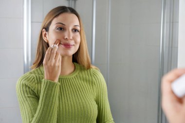 Yüz için elektrikli epilatör. Genç bir kadının portresi aynada kendine bakıyor bıyıktaki kılları alarak. Yüz bakımı.