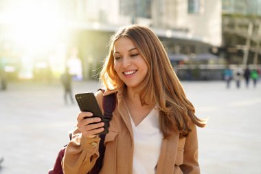 Şaşkın öğrenci kız izliyor. Şehir caddesinde akıllı telefonu heyecanlıydı.