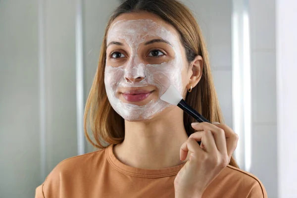 Mujer Joven Aplicando Mascarilla Hidratante Con Cepillo Lámina Facial Mira — Foto de Stock