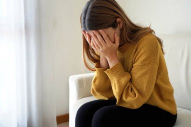 Depresyonda olan üzgün, güzel bir kadın evde endişeli bir şekilde ağlıyor.