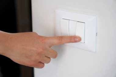 Enerji tasarrufu. Işıklandırma düğmesinde kadın parmağı kapalı..