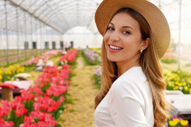 Hasır şapkalı taze kızın yakın çekimi baharda bahçede kameraya döner.