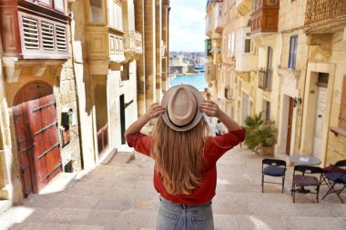 Malta 'da turizm. Şapkalı turist kız, UNESCO Dünya Mirası 'nın eski Valletta kasabası Malta' da merdivenlerden iniyor..