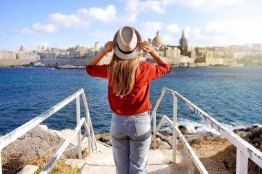 Malta 'da tatiller. Akdeniz 'in mavi suyuyla Valletta şehir manzarasının tadını çıkaran güzel bir kızın arka manzarası..