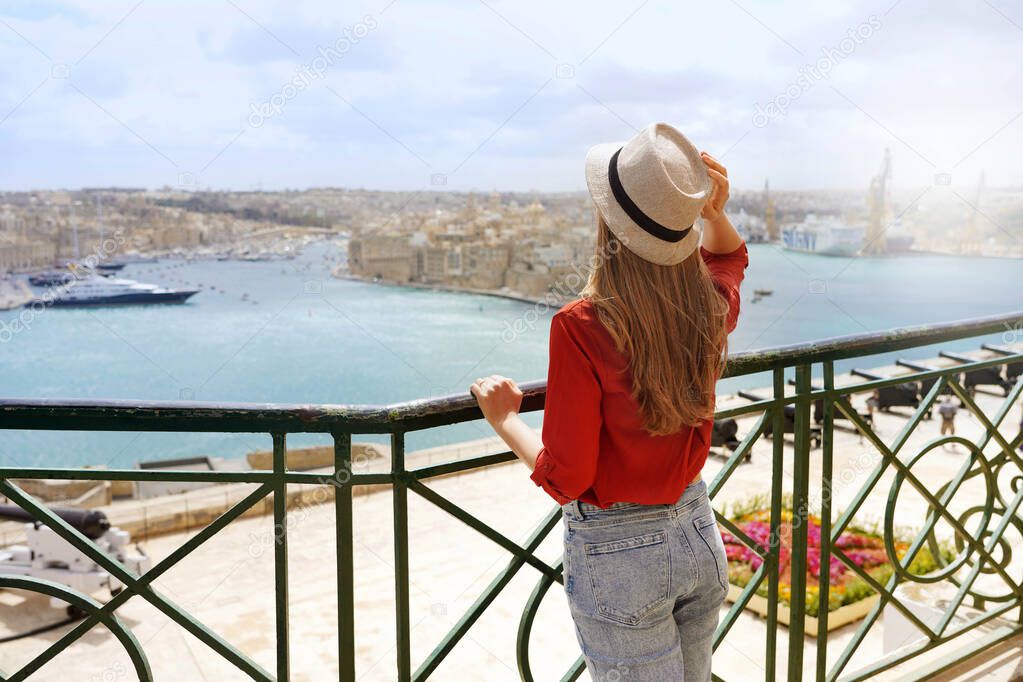 Tourism in Malta. Back view of beautiful girl enjoying view of Three Cities from Upper Barrakka Gardens, Valletta, Malta.