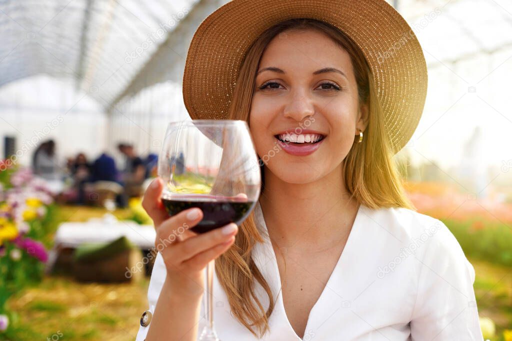 Photo of happy cheerful woman holds wine glass makes toast lookng at camera isolated on greenhouse background