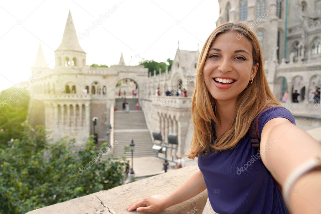 Traveler girl taking selfie on sunset in Budapest, Hungary. Young tourist woman takes self portrait on Fisherman's Bastion in the Castle District of Budapest, Hungary.