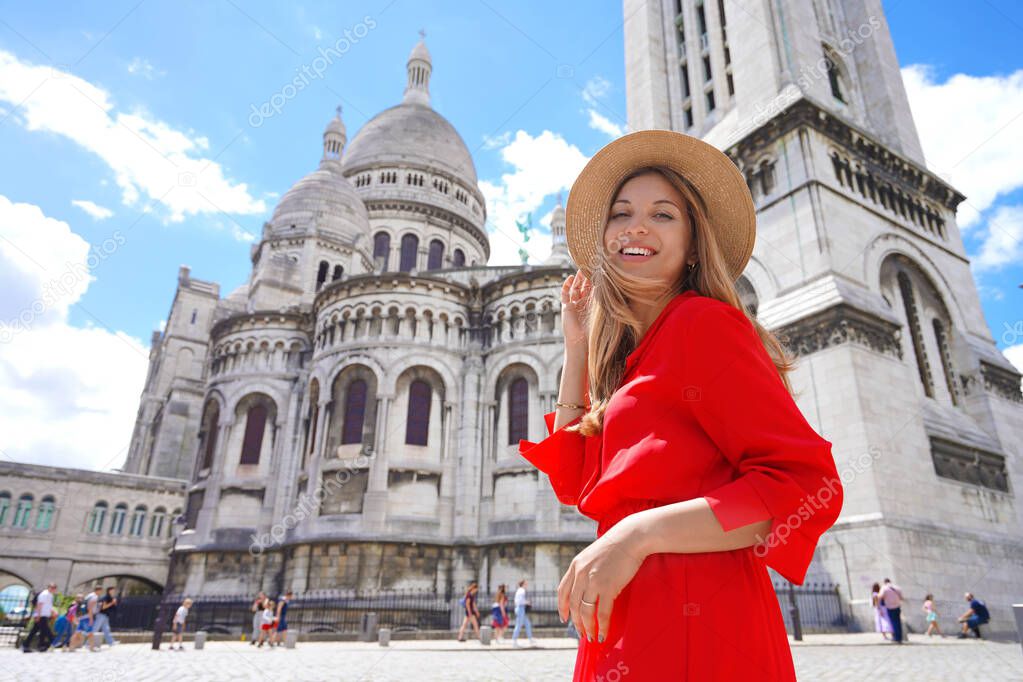 Fashion model walking in Paris with the Basilica of the Sacred Heart of Paris on the background. Smiling at camera. Low angle.