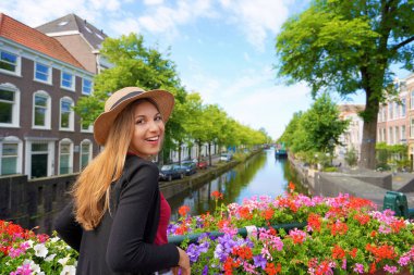 Hollanda, Lahey 'deki kanalda çiçek saksıları arasında kameraya bakan genç turist portresi