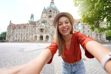 Beautiful young woman takes selfie photo in front of Hanover city hall, Germany