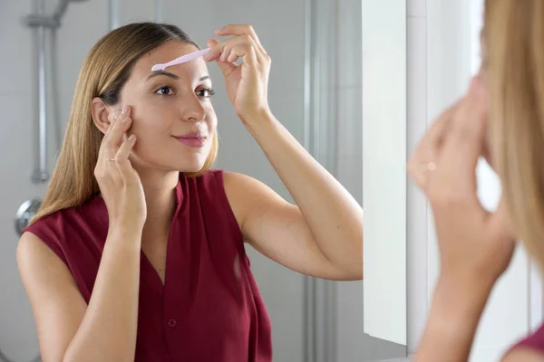 Hispanic Woman Shaving Her Eyebrows Razor Mirror Home — Foto de Stock