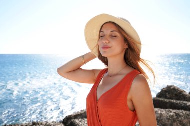 Plajdaki lüks tatil beldesinde temiz havanın tadını çıkaran genç moda kadınının portresi. Yaz tatili ve rahatlama konsepti